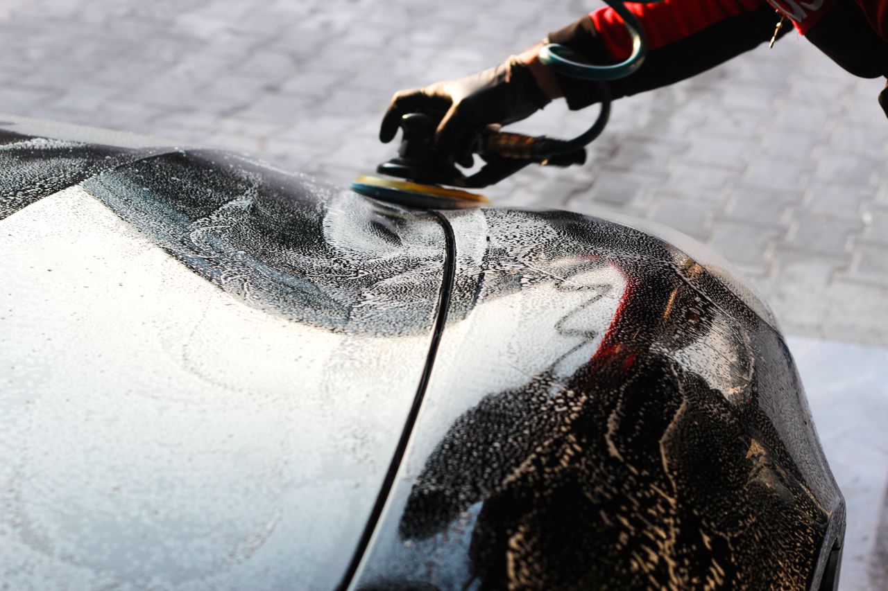 Close-up of a car being polished by hand, showcasing professional detailing and maintenance.